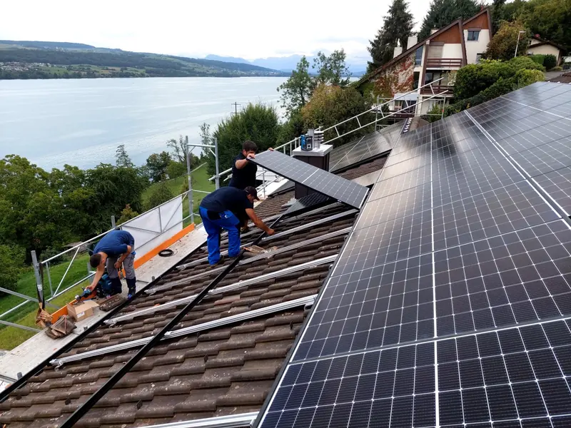 Monteure von Future Power verlegen Solarmodule auf einem Ziegeldach über einem See