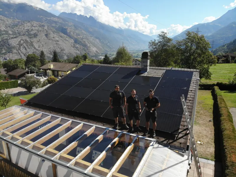 Drei Monteure von Future Power auf einem Dach mit fertiger Solaranlage vor Bergkulisse
